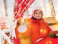 Christmas child portrait bokeh lights festive decorations Little girl in red warm jacket riding in carriage snowy winter.