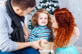 Christmas happy family of three persons and fir tree with gift boxes over white bedroom background Royalty Free Stock Photo