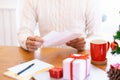 Christmas and Happy New Year blessing concept. Man wearing white sweater writing and sending greeting card
