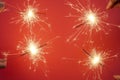 Christmas or Happy New Year party banner concept. Close up of Bright burning four sparklers on a red Royalty Free Stock Photo