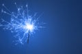 Christmas or Happy New Year party concept. Close up of Bright burning sparkler on a blue background Royalty Free Stock Photo