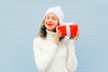 Christmas happy smiling young woman with gift box wearing a knitted hat sweater over blue Royalty Free Stock Photo