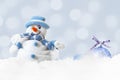 Funny blue snowman on xmas lights bokeh background, white snowflakes, merry Christmas and happy new year card concept Royalty Free Stock Photo