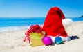 Christmas hat with gift box and christmas balls on the beach Royalty Free Stock Photo