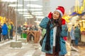 Christmas hat, gifts in the city street with snow. Happy girl laughing. Royalty Free Stock Photo