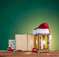 Christmas hat, lantern, book and clock on a green backgr