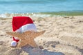 Christmas cap on starfish in sand Royalty Free Stock Photo