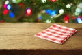 Christmas holiday background with empty wooden table with red checked tablecloth over Christmas tree bokeh. Product montage Royalty Free Stock Photo