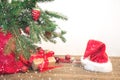 Christmas holiday background. Gifts with a red ribbon, Santa`s hat and decor under a Christmas tree on a wooden board. Copy space Royalty Free Stock Photo