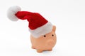 Christmas holiday bonus and expenses. Piggy bank with Santa hat isolated on white