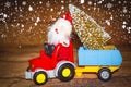 Christmas holiday celebration theme. Santa Claus carries Christmas tree on tractor with trailer.