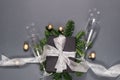 Black handmade gift boxes decorated with silver ribbon, tree branches, two glasses champagne confetti on gray background. Royalty Free Stock Photo