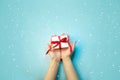 Christmas Holiday Composition. New Year Gift in White Box with Red Ribbon in Female Hands on Light Blue Background Flat Lay Top Vi Royalty Free Stock Photo