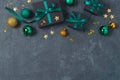 Christmas holiday concept with black gift boxes, green ribbons and decorations on dark background. Top view, flat lay