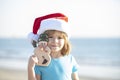 Christmas holiday concept. Child Santa with toy smowman on the sunset sea. Santa and snowman on summer beach, concept Royalty Free Stock Photo