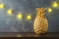 Christmas holiday concept with pineapple as alternative Christmas tree and lights garland on dark background