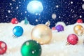 Christmas Holiday with deep blue sky with moonlight at night, a full moon and a group of christmas balls and decorations on snow. Royalty Free Stock Photo