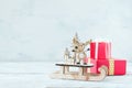 Christmas holiday festive theme with wooden cute reindeer on sled, red gift boxes on white rustic background