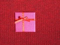 Christmas holiday gift in small color box covered with ribbon with bow against red background of woolen knitted fabric top view Royalty Free Stock Photo