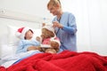 Christmas holiday in hospital happy child lying in bed with Santa Claus hat and nurse dressing a teddy bear