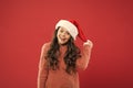 Christmas holiday invitation concept. Playful cutie. Adorable girl with long curly hair wear santa claus hat red Royalty Free Stock Photo