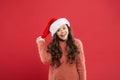 Christmas holiday invitation concept. Playful cutie. Adorable girl with long curly hair wear santa claus hat red Royalty Free Stock Photo