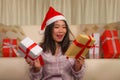 Christmas holiday lifestyle portrait at home of young beautiful and happy Asian American woman in pajamas and Santa hat  holding Royalty Free Stock Photo