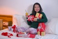 Christmas holiday lifestyle portrait of young happy and sweet Asian Chinese woman sitting on bed preparing xmas presents wrapping Royalty Free Stock Photo