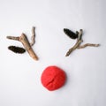 Christmas holiday minimal concept. Santas reindeer made of cones and wooden details and red yarn ball on white background.