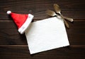 Christmas Holiday Paper Card with Red and White Santa Claus Hat and fork and spoon on Dark Rustic Wood Table Background. Royalty Free Stock Photo