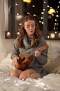 Happy young woman playing guitar in bed at home Royalty Free Stock Photo