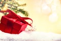 Christmas holiday setting with present in red box over snow Royalty Free Stock Photo