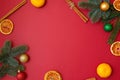 Christmas holidays composition on red background with copy space for your text. Xmas tree branches in the corners, dried oranges, Royalty Free Stock Photo