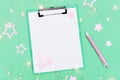 Christmas holidays concept, mock up white sheet for wish list. New Year glowing garland, pink stars and notebook Royalty Free Stock Photo