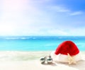 Christmas holidays concept. Santa claus hat and starfish on summer sand beach Royalty Free Stock Photo