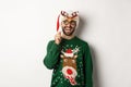 Christmas and holidays concept. Smiling beared man in Santa hat looking happy, holding party mask for New Year