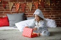 Christmas Holidays. Cute girl 8-9 years, sits on bed with a box in his hands.