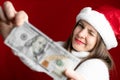 Christmas, holidays and finance concept - Happy Smiling young woman in Santa helper hat holding dollar money banknote Royalty Free Stock Photo