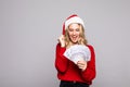 Christmas, holidays and finance concept. Winner young woman in santa helper hat holding dollar money banknotes isolated over grey Royalty Free Stock Photo