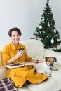 Christmas, holidays and people concept - happy young woman reading book at home. Royalty Free Stock Photo