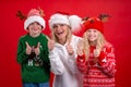 Christmas Holidays Portrait happy family of three In Santa hats mother and kids standing and Smiling on red studio Royalty Free Stock Photo