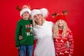 Christmas Holidays Portrait happy family of three In Santa hats mother and kids standing and Smiling on red studio Royalty Free Stock Photo