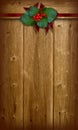 Christmas holly bouquet and ribbons on brown barn wall.