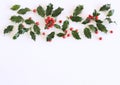 Christmas holly with red berries. Traditional festive decoration. Holly branch with red berries on white table Royalty Free Stock Photo