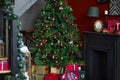 Christmas home decor. large elegant green tree with a garland, balls, gifts. dark wooden fireplace and staircase