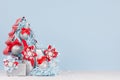 Christmas home decor in pastel blue and red color - decorative christmas tree with balls and gift boxes on white wood board. Royalty Free Stock Photo