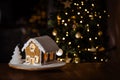 Ginger house in Christmas and festive mood and Christmas tree in background Royalty Free Stock Photo