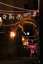 Christmas illumination, girdyands, star of the Magi. Dark nightly narrow streets of the old city,