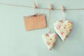 Christmas image of fabric hearts and empty card for adding text hanging on rope in front of blue wooden background. retro filtered Royalty Free Stock Photo