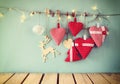 Christmas image of fabric red hearts and garland lights, hanging on rope in front of blue wooden background. retro filtered. Royalty Free Stock Photo